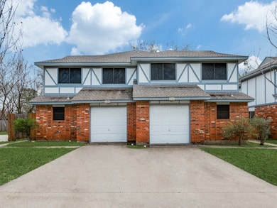English style home featuring a shingled roof, driveway, stucco siding, and brick siding