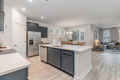 Kitchen with sink, light hardwood / wood-style flooring, stainless steel appliances, an island with sink, and decorative light fixtures