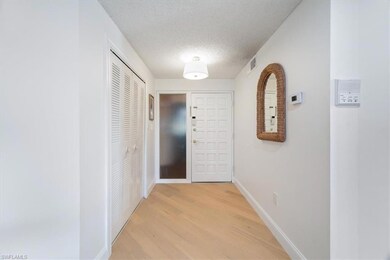 Corridor featuring a textured ceiling, light wood-style flooring, and baseboards