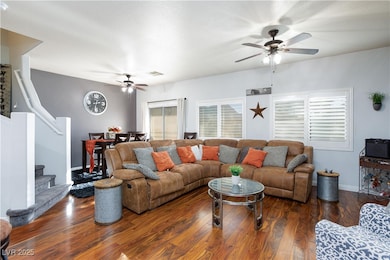 Living area featuring wood finished floors, stairs, a ceiling fan, and a textured ceiling