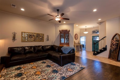 Living room with hardwood / wood-style flooring, a ceiling fan, recessed lighting, crown molding, and stairway
