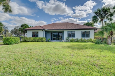 Back of house featuring a tiled roof, a lawn, fenc