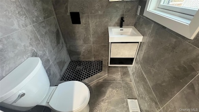 Bathroom with tile walls, vanity, and tiled shower