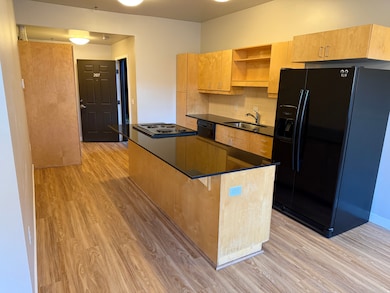 Kitchen featuring black appliances, open shelves, light brown cabinetry, and backsplash