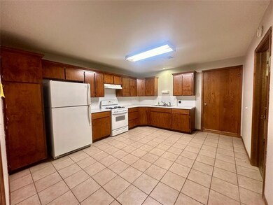 Kitchen with light tile patterned floors, sink, and white appliances