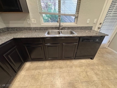 Kitchen with black dishwasher, a textured wall, li