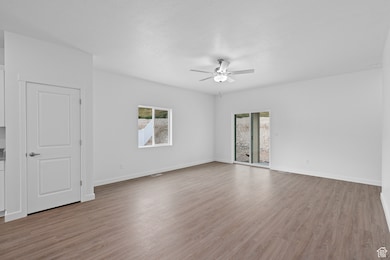 Unfurnished room with a wealth of natural light, a ceiling fan, and wood finished floors