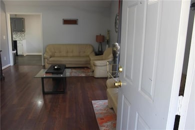 Living area with dark wood-type flooring and baseboards