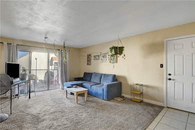 Carpeted living area featuring tile patterned floors and a textured ceiling