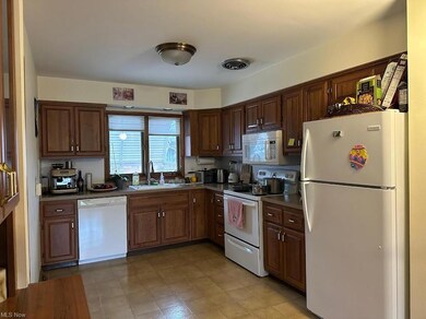 Kitchen with white appliances, dark brown cabinetry, and light tile floors