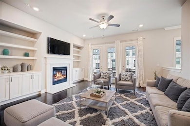 Living area with a ceiling fan, dark wood-style floors, a high end fireplace, recessed lighting, and built in features