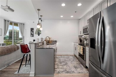 Kitchen with stainless steel appliances, a peninsula, light stone counters, recessed lighting, and light wood-type flooring