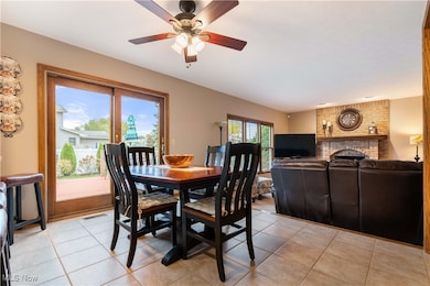 Dining space featuring a brick fireplace, light tile patterned flooring, and a ceiling fan