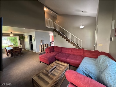 Carpeted living room with high vaulted ceiling. Vi