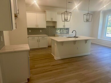 Kitchen featuring tasteful backsplash, quartz  countertops, white cabinetry, a kitchen breakfast bar, and crown molding