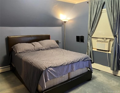 Bedroom featuring vaulted ceiling, dark colored carpet, a baseboard heating unit, and cooling unit