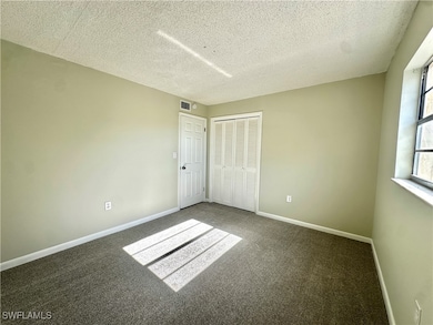 Empty room featuring a textured ceiling and carpet