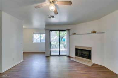Unfurnished living room featuring wood finished floors, a tile fireplace, a textured ceiling, and a ceiling fan