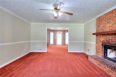 Unfurnished living room featuring carpet, a brick fireplace, a textured ceiling, ceiling fan, and a chandelier