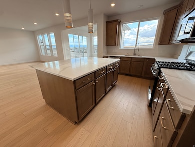 Kitchen with a kitchen island, gas range oven, light stone countertops, light wood-type flooring, and recessed lighting