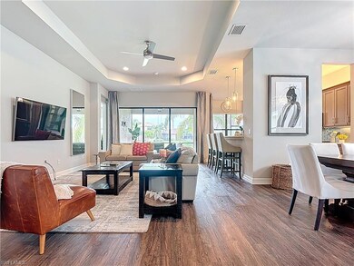 Living room with wood finished floors, a raised ceiling, ceiling fan, and recessed lighting