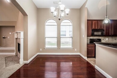Kitchen with decorative light fixtures, dark brown cabinets, dark hardwood / wood-style flooring, a premium fireplace, and decorative backsplash