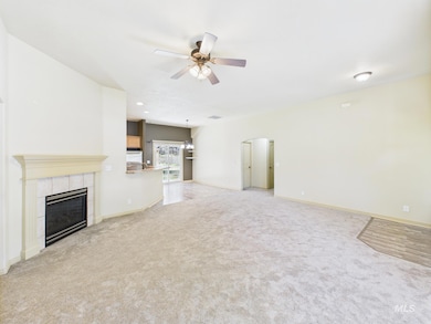 Unfurnished living room featuring ceiling fan, light colored carpet, arched walkways, a tiled fireplace, and recessed lighting