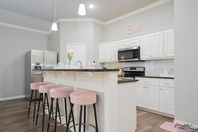 Kitchen with stainless steel appliances, crown molding, wood finished floors, a breakfast bar, and decorative backsplash