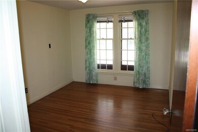 downstairs bedroom with hardwood and large window.