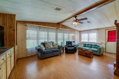 A second view of the living room highlights the inviting layout, warm wood-toned flooring, and generous space—perfect for everyday relaxation or entertaining.
