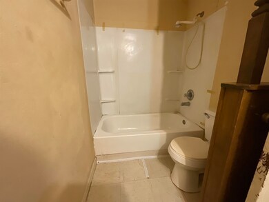 Bathroom featuring tile flooring, toilet, and bath