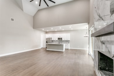 Unfurnished living room with high vaulted ceiling, light wood-type flooring, a high end fireplace, recessed lighting, and ceiling fan