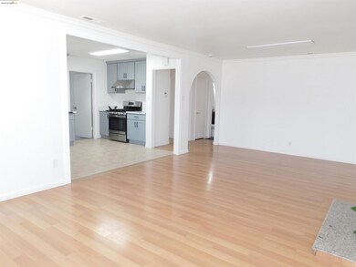 Unfurnished living room with arched walkways, ornamental molding, and light wood-style flooring