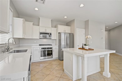 Kitchen featuring stainless steel appliances, white cabinetry, light tile patterned floors, recessed lighting, and a breakfast bar