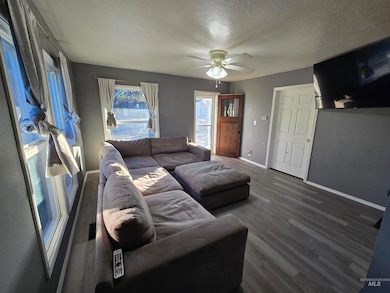 Living room with dark wood-type flooring, a textured ceiling, and ceiling fan