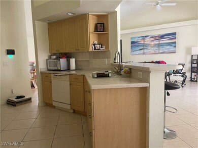 Kitchen with sink, a breakfast bar area, kitchen peninsula, white appliances, and ceiling fan