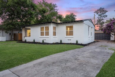 View of front of property with brick siding, a lawn, a garage, and an outdoor structure