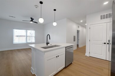 Kitchen featuring a sink, dishwasher, light wood-