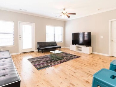 Living room with ornamental molding, light wood-type flooring, and a ceiling fan