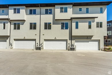 Rear view of house with stucco siding, a garage, and driveway