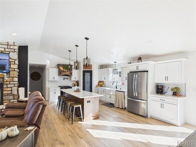 Kitchen with a kitchen bar, open floor plan, hanging light fixtures, lofted ceiling, and freestanding refrigerator