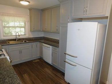Kitchen with white appliances and dark wood-style flooring