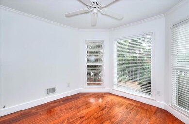 Bright front office/bonus room right of entrance featuring crown molding, wood finished floors, and a ceiling fan.