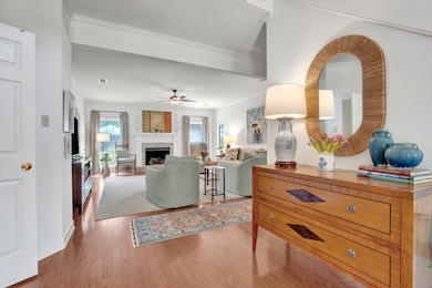Living room featuring wood finished floors, ceiling fan, a fireplace, and ornamental molding