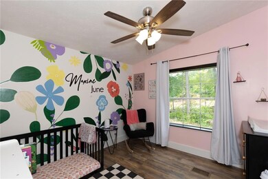 Bedroom featuring wood finished floors, a nursery area, ceiling fan, and lofted ceiling