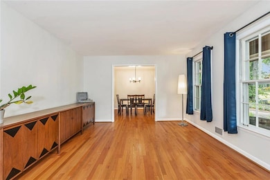 Unfurnished room featuring light wood-style flooring, a chandelier, and baseboards