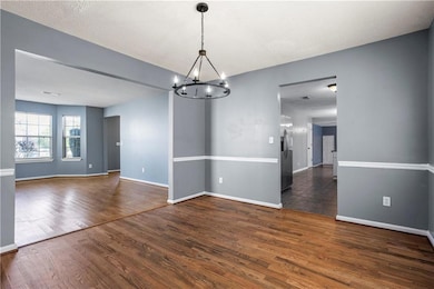 Empty room with baseboards, a notable chandelier, 