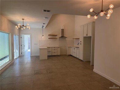 Kitchen with a chandelier, pendant lighting, open shelves, light countertops, and wall chimney exhaust hood