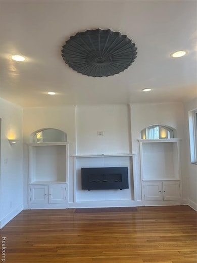 Unfurnished living room with recessed lighting, built in shelves, and wood finished floors