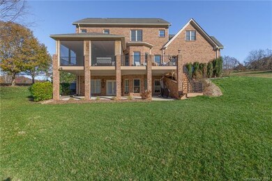 View of the back of the home and all the outdoor entertaining space!  Stairs leading down from the upper deck, covered lower patio, upper screened deck and outdoor grill area with propane hook up.